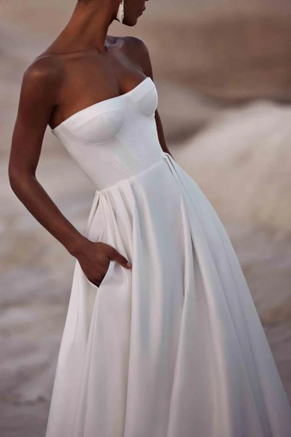Un abito da sposa in raso bianco con strascico a palazzo e senza spalline